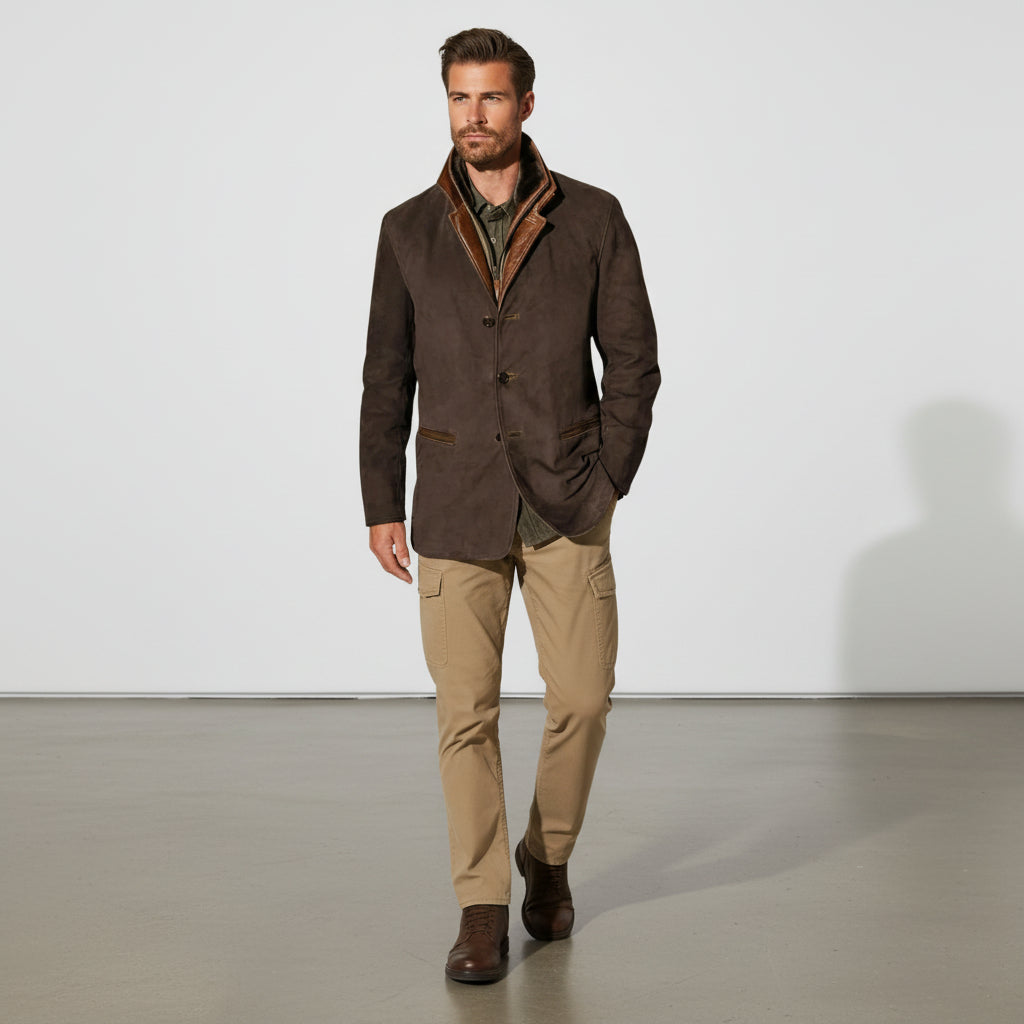 Man wearing a brown jacket and beige pants standing against a white background